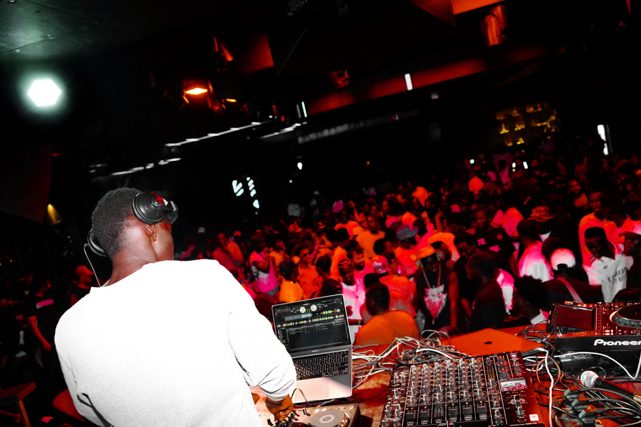 DJ AG Luxurious performing behind the DJ booth in a packed nightclub